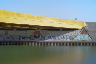 View across the Mittelland Canal to the underside and the graffiti-painted abutment of a bridge on
