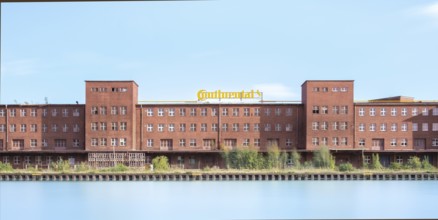 View across the Mittelland Canal to an industrial building with trees growing in front of it, long