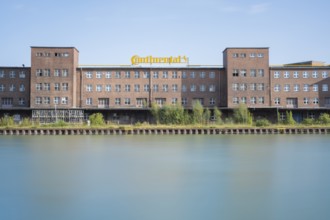View across the Mittelland Canal to an industrial building with trees growing in front of it, long