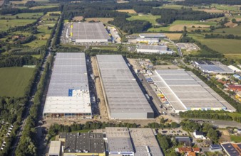 Large warehouses in an industrial area, framed by fields and scattered trees, aerial view Werl