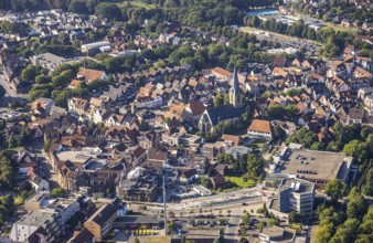 Close-up of the town centre with a prominent church surrounded by houses and green areas, aerial