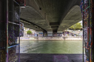 View under a bridge with graffiti on the walls over a river, Am Donaukanal Innere Stadt Vienna