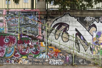 Diverse graffiti with lettering on a concrete wall next to a staircase, Am Donaukanal Innere Stadt