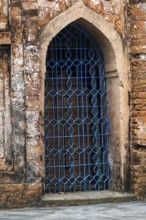 An ornate blue-metal gate set in a rustic old brick archway-Dhaka, Bangladesh