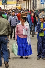 Woman in traditional dress with bag walking through a busy street, Traditionally dressed woman in