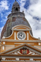 Architecturally richly decorated tower with clock and coat of arms under a cloudy sky, The