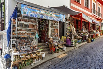 Steep street with shops selling pottery and souvenirs. Colourful facades create a nostalgic market
