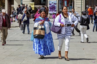 Two woman in traditional and modern dress walk on a busy street, Traditionally dressed woman in the