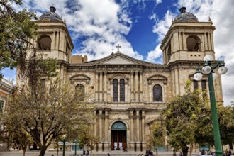 Historic cathedral with imposing façade and towers under a cloudy sky in an urban setting, A church