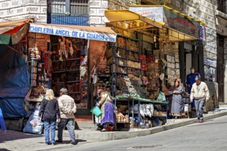 A busy market stall with souvenirs on a street corner surrounded by people, The witches' market of