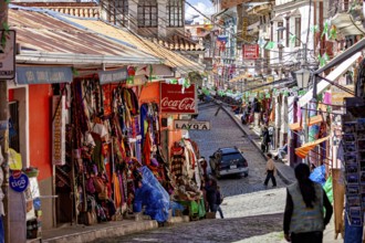 A lively street with colourful shops and people in a mountainous setting, the witches' market in La