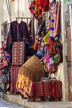A shop in a narrow street offers colourful, handmade textiles and clothing with traditional