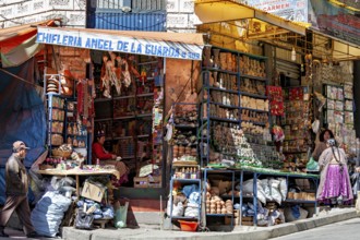 A street scene with a stall full of colourful goods and people in traditional dress, the witches'
