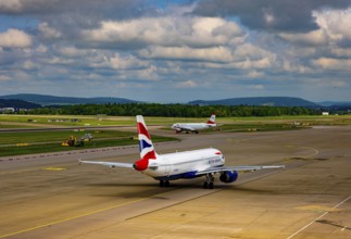British Airways and Austrian Airlines Passenger Airplane Taxiing on Runway in a Sunny Summer Day
