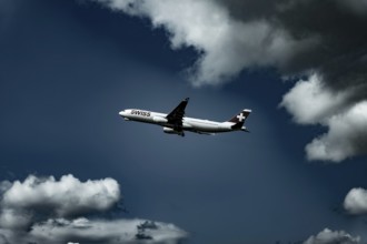 Swiss Airlines Passenger Airplane Flying Against Blue Sky and Clouds in a Sunny Summer Day From the