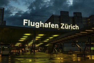 Illuminated Entrance Sign to Zurich Airport and a Bus Station at Night in the Airport in Kloten,