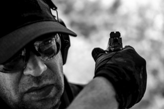 Man with Cap and Protection Eyeglasses Holding a Handgun Backward in Switzerland