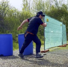Man with Cap and Protection Eyeglasses Running and Holding a Handgun Backward in IPSC Shooting