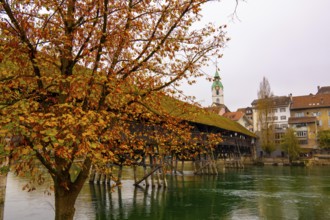 Old Town and the Historical Covered Wood Bridge Holzbrücke over River Aare in an Autumn Day in