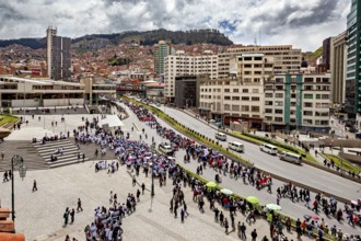 City view with crowd on square and street, surrounded by high buildings and mountains in the
