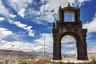An artistically designed stone gate with a view of a city and clouds in the sky, The gate at the
