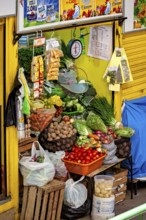 Varied vegetable stall with fresh, colourful vegetables in a balanced presentation, small shops and