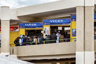 Crowd in front of stalls with blue signs in a modern market complex, Small shops and restaurants in