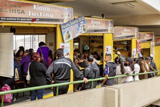 Lots of people gather at yellow market stalls, lively shopping atmosphere, small shops and