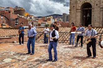 Music group on a city tiled roof in front of an architectural backdrop with a cloudy sky, A music
