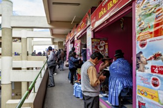 Market goers in lively surroundings at food stalls, some wearing traditional clothing, Small shops
