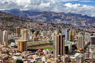 City panorama of La Paz with tall buildings and mountains behind under a cloudy sky, The houses and