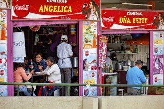A busy street snack bar with people sitting at tables and eating, surrounded by colourful