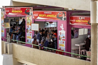 Lively food stalls with smiling people and Coca-Cola adverts, convivial atmosphere, small shops and