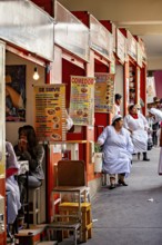 Lively market with food stalls and seated people in colourful, lively surroundings, Small shops and