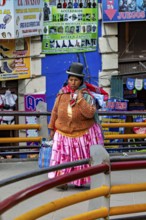 A woman in traditional dress walks through a colourful market street in Bolivia, A traditional