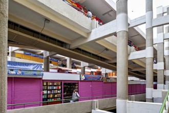 Interior view of a multi-storey market with colourful facades and various stalls, small shops and