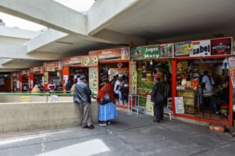 Lively marketplace with various stalls and customers dressed in traditional clothing, small shops