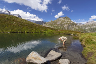 Hiker refreshes himself in the Salzbodensee lake on the glacier show trail in the Tauerntal valley,