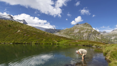 Hiker refreshes himself in the Salzbodensee lake on the glacier show trail in the Tauerntal valley,
