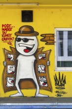 Funny comic-style graffiti with a figure in a trench coat on a yellow wall, at the harbour in Linz,