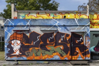 Colourful graffiti wall with lively figures and letters in an urban environment, at the port of