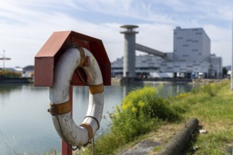 Lifebuoy in the foreground with industrial backdrop on a sunny day, at the harbour of Linz Upper