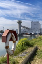 Lifebuoy in front of an industrial area in a partly cloudy sky, at the harbour of Linz Upper