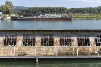 Dilapidated industrial building with destroyed windows directly on the waterfront, at the harbour