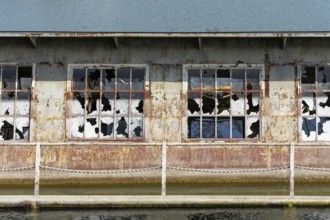 Close-up of broken windows of a rusty building on the waterfront, at the harbour of Linz Upper
