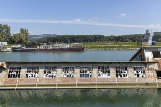 Ruins of an industrial building in the water with a ship in the background, at the harbour of Linz