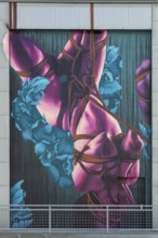 Colourful depiction of a body decoratively wrapped with flowers and ribbons, at the port of Linz,