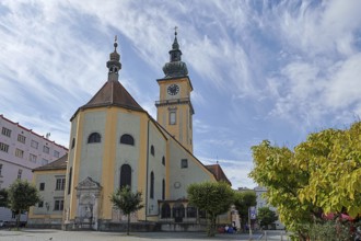 Baroque church with clock tower and trees on a sunny square, blue sky, Stadtpfarrkirche Maria