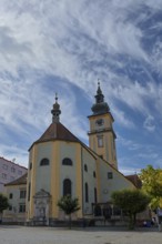 Baroque church with clock tower on a square under a partly cloudy sky, Stadtpfarrkirche Maria