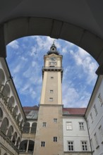 View through an arch onto a historic clock tower with blue sky, Arkardenhof Landhaus Linz Upper